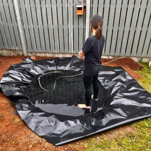 Farah filling a pond liner with water during the construction of a DIY natural pond