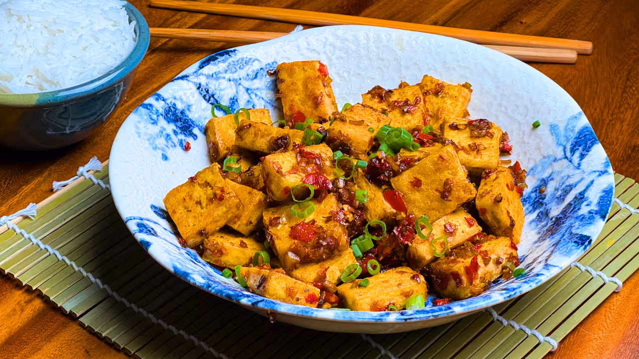 Crispy vegan lemongrass tofu with chillies and garlic on a serving plate.
