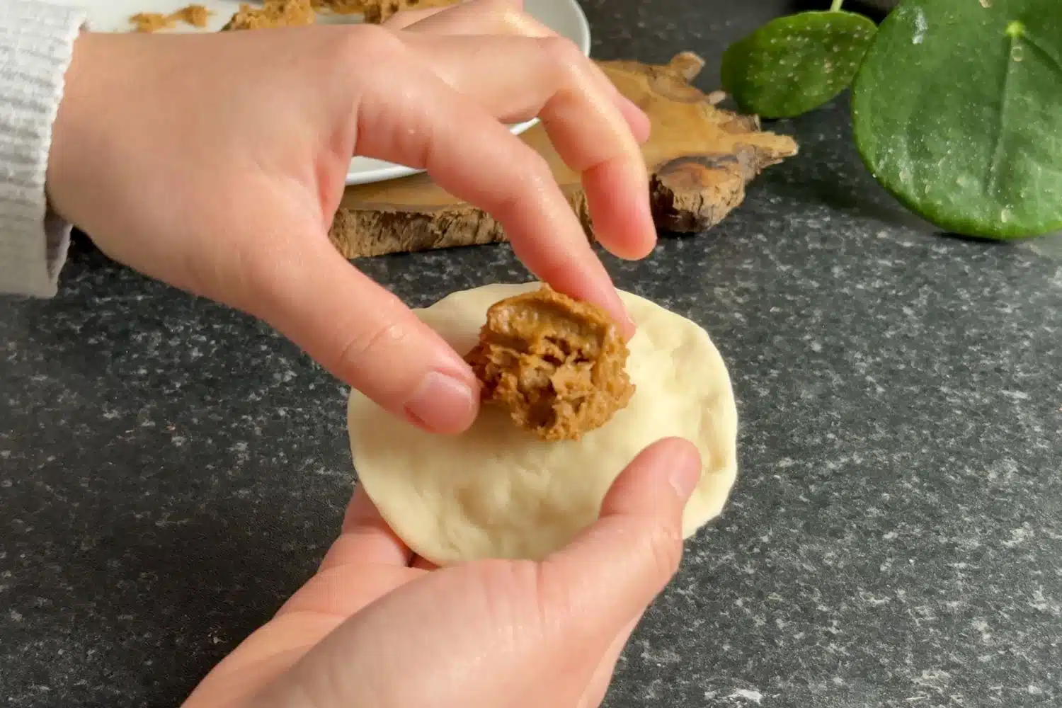 Filling steamed bun dough with Lotus Biscoff spread before sealing